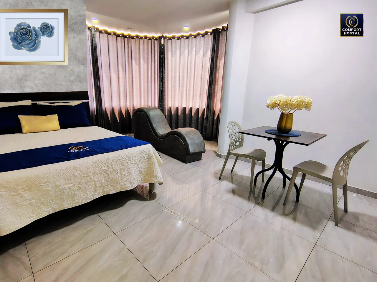 Habitación Comfort Queen con cama, mesa y amplias ventanas